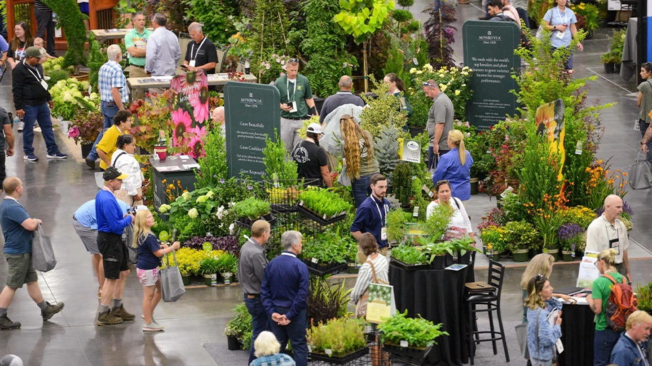 Trade show floor filled with plants and people browsing.