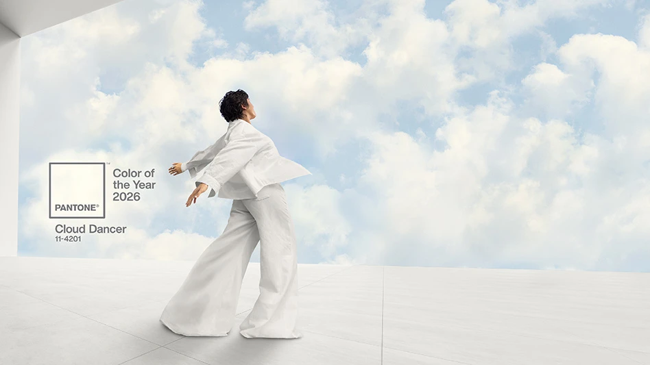 Rows of red poinsettias in a greenhouse. There are more green plants hanging from tracks near the roof.