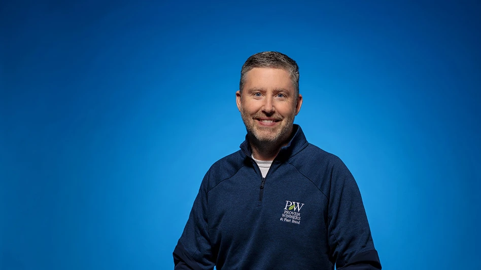 A man wearing a navy blue sweater on a blue background.