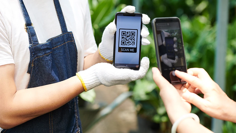 a person with white gloves holding a phone with a qr code that reads scan me